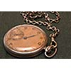 Very old clock with chain lying on rough green  surface - shallow depth of field