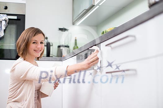 Young woman doing housework, cleaning the kitchen