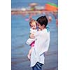 happy young mother walking on beach and push baby carriage