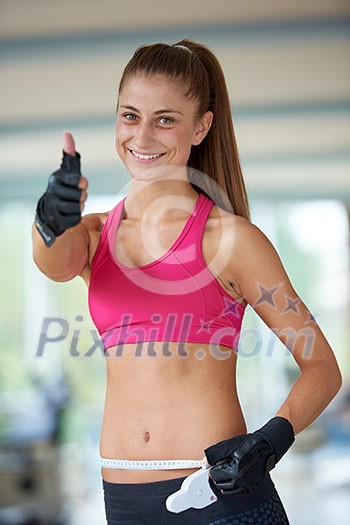 young fit woman measuring belly on a training in fitness gym young fit woman measuring belly on a training in fitness gym