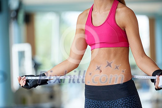 young fit woman measuring belly on a training in fitness gym young fit woman measuring belly on a training in fitness gym
