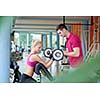 young sporty woman with trainer exercise weights lifting in fitness gym