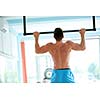 handsome young man in fitness gym lifting up and hanging while working on hands and back muscles