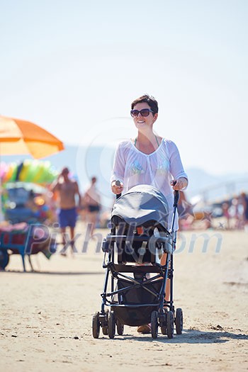 happy young mother walking on beach and push baby carriage happy young mother walking on beach and push baby carriage