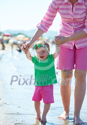 happy mom and baby on beach have fun while learning to walk and make first steps happy mom and baby on beach have fun while learning to walk and make first steps