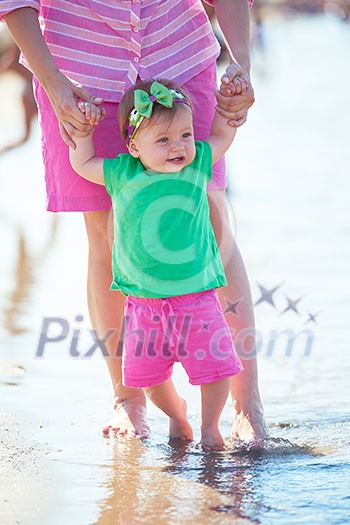 happy mom and baby on beach have fun while learning to walk and make first steps happy mom and baby on beach have fun while learning to walk and make first steps