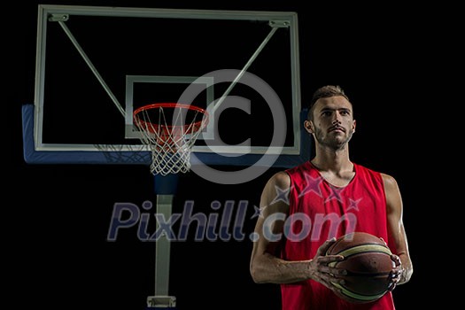 Basketball player portrait on basketball court holding ball with black isolated background Basketball player portrait on basketball court holding ball with black isolated background