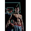 Basketball player portrait  on basketball court holding ball with black isolated background