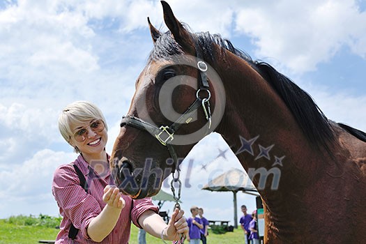 happy woman in sunglasses sitting on horse farm animal outdoors with blue sky in background happy woman in sunglasses sitting on horse farm animal outdoors with blue sky in background