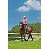 happy woman in sunglasses sitting on horse farm animal outdoors with blue sky in background