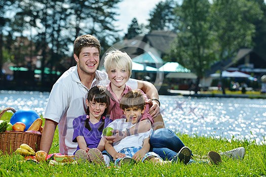Happy young family playing together with kids and eat healthy food in a picnic outdoors Happy young family playing together with kids and eat healthy food in a picnic outdoors