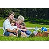 Happy young  family playing together with kids and eat healthy food  in a picnic outdoors