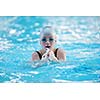 Happy muscular swimming woman  wearing glasses and cap at swim pool and represent health and fit concept