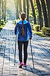 Nordic walking adventure and exercising concept - woman hiking withnordic walking poles in park