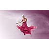 Young attractive woman in pink dress jumping high