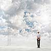 Rear view of businesswoman standing near ladder going high in sky