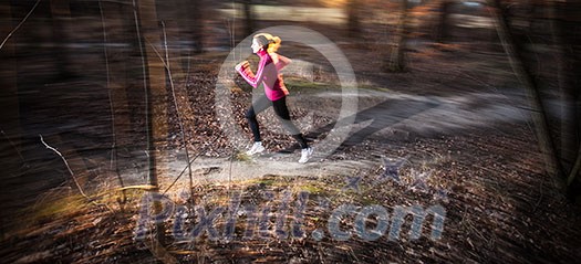 Young woman running outdoors in a city park on a cold fall/winter day (motion blurred image) Young woman running outdoors in a city park on a cold fall/winter day (motion blurred image)