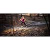 Young woman running outdoors in a city park on a cold fall/winter day (motion blurred image)