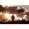 Adventurous man observing a lovely sunset in nature, alone, standing proudly