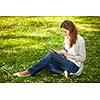 Young woman using her tablet computer while relaxing outdoors in a park on a lovely spring day