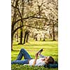 Young woman using her tablet computer while relaxing outdoors in a park on a lovely spring day