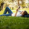 Young woman using her tablet computer while relaxing outdoors in a park on a lovely spring day