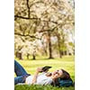 Young woman using her tablet computer while relaxing outdoors in a park on a lovely spring day