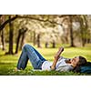 Young woman using her tablet computer while relaxing outdoors in a park on a lovely spring day