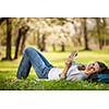 Young woman using her tablet computer while relaxing outdoors in a park on a lovely spring day