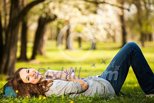 Young woman using her tablet computer while relaxing outdoors in a park on a lovely spring day Young woman using her tablet computer while relaxing outdoors in a park on a lovely spring day