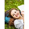 Young woman using her tablet computer while relaxing outdoors in a park on a lovely spring day