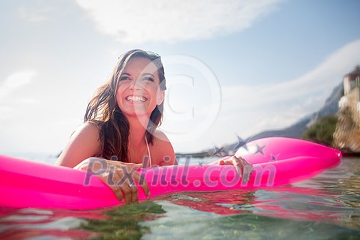 Pretty, young woman enjoying a day at the beach, relaxing on inflatable mattress Pretty, young woman enjoying a day at the beach, relaxing on inflatable mattress