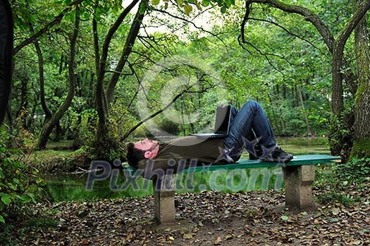 one young businessman working on laptop outdoor with green nature in background one young businessman working on laptop outdoor with green nature in background