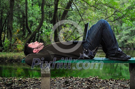 one young businessman working on laptop outdoor with green nature in background one young businessman working on laptop outdoor with green nature in background