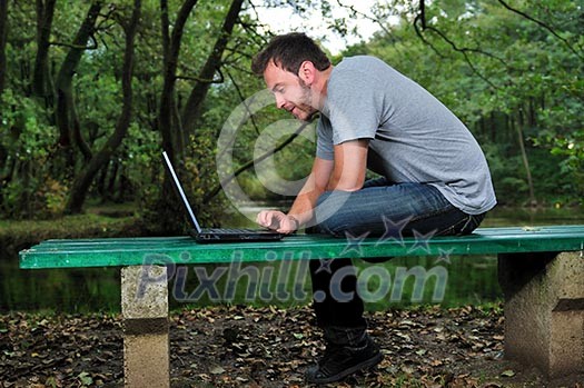 one young businessman working on laptop outdoor with green nature in background one young businessman working on laptop outdoor with green nature in background