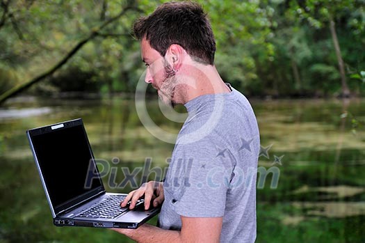 one young businessman working on laptop outdoor with green nature in background one young businessman working on laptop outdoor with green nature in background