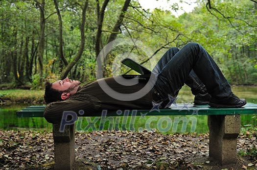 one young businessman working on laptop outdoor with green nature in background one young businessman working on laptop outdoor with green nature in background