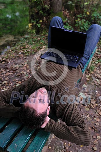 one young businessman working on laptop outdoor with green nature in background one young businessman working on laptop outdoor with green nature in background