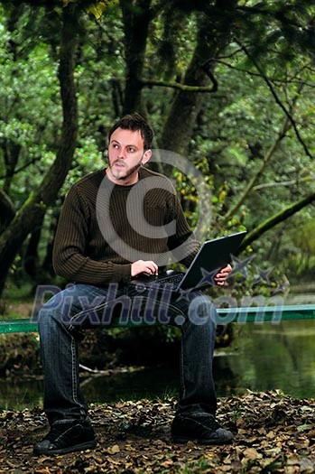 one young businessman working on laptop outdoor with green nature in background one young businessman working on laptop outdoor with green nature in background