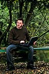 one young businessman working on laptop outdoor with green nature in background