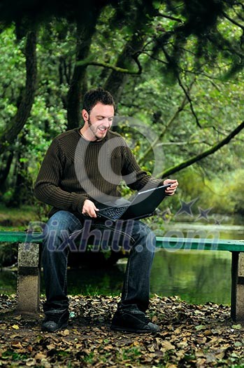 one young businessman working on laptop outdoor with green nature in background one young businessman working on laptop outdoor with green nature in background