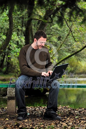 one young businessman working on laptop outdoor with green nature in background one young businessman working on laptop outdoor with green nature in background