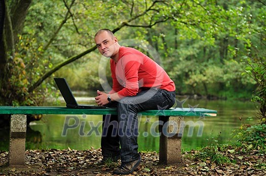 one young businessman working on laptop outdoor with green nature in background one young businessman working on laptop outdoor with green nature in background