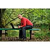 one young businessman working on laptop outdoor with green nature in background