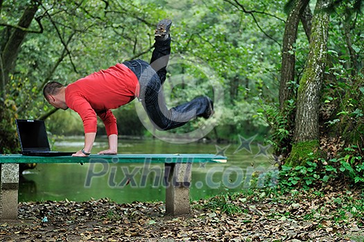 young businessman jump over edge with laptop and green nature in background young businessman jump over edge with laptop and green nature in background