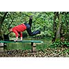 young businessman jump over edge with laptop and green nature in background