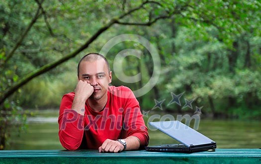 one young businessman working on laptop outdoor with green nature in background one young businessman working on laptop outdoor with green nature in background