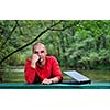 one young businessman working on laptop outdoor with green nature in background