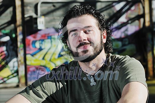 happy young man posing outdoor in urban enviroment with graffiti in background happy young man posing outdoor in urban enviroment with graffiti in background