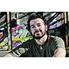 happy young man posing outdoor in urban enviroment with graffiti in background 